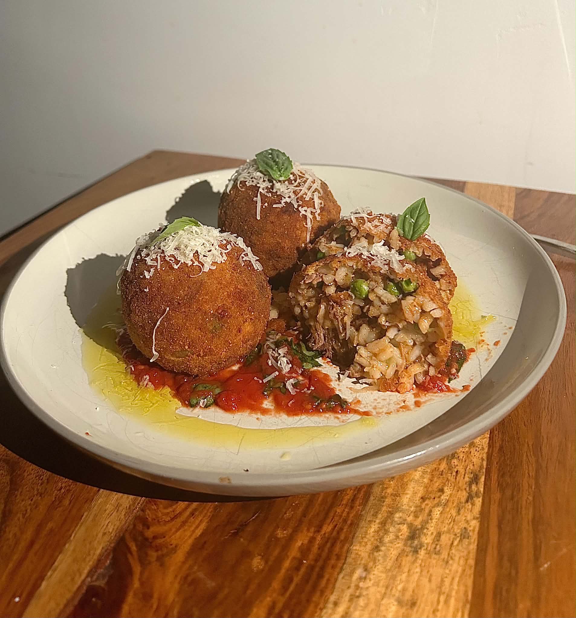 Fried arancini over ragu sauce with shaved parmesan