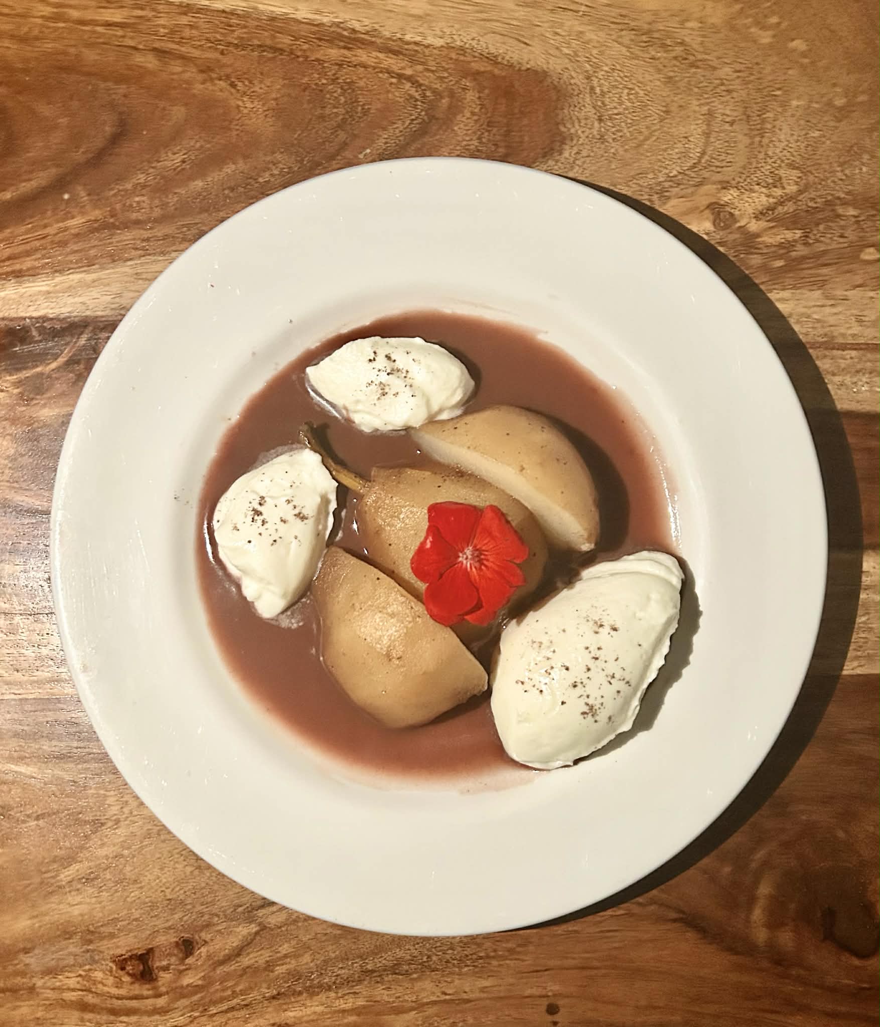 Poached pear dessert with whipped mascarpone and an edible flower
